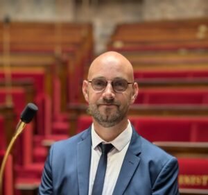 Portrait de Thomas Nastorg dans l’hémicycle vide de l’Assemblée nationale, lieu du débat démocratique français.